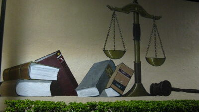 A painting of a scale of books and a gavel