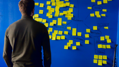 A person looking at a blue wall with yellow sticky notes